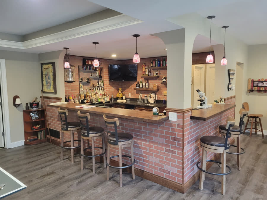 Finished basement with a brick-front bar and bar stools